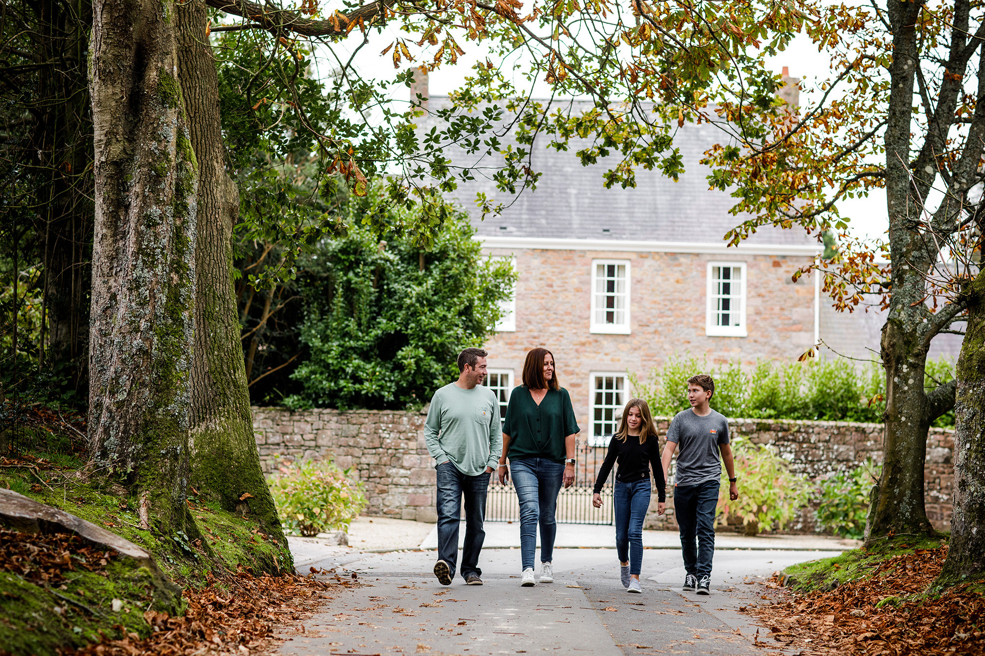 A family walk past a period house in the Jersey countryside.