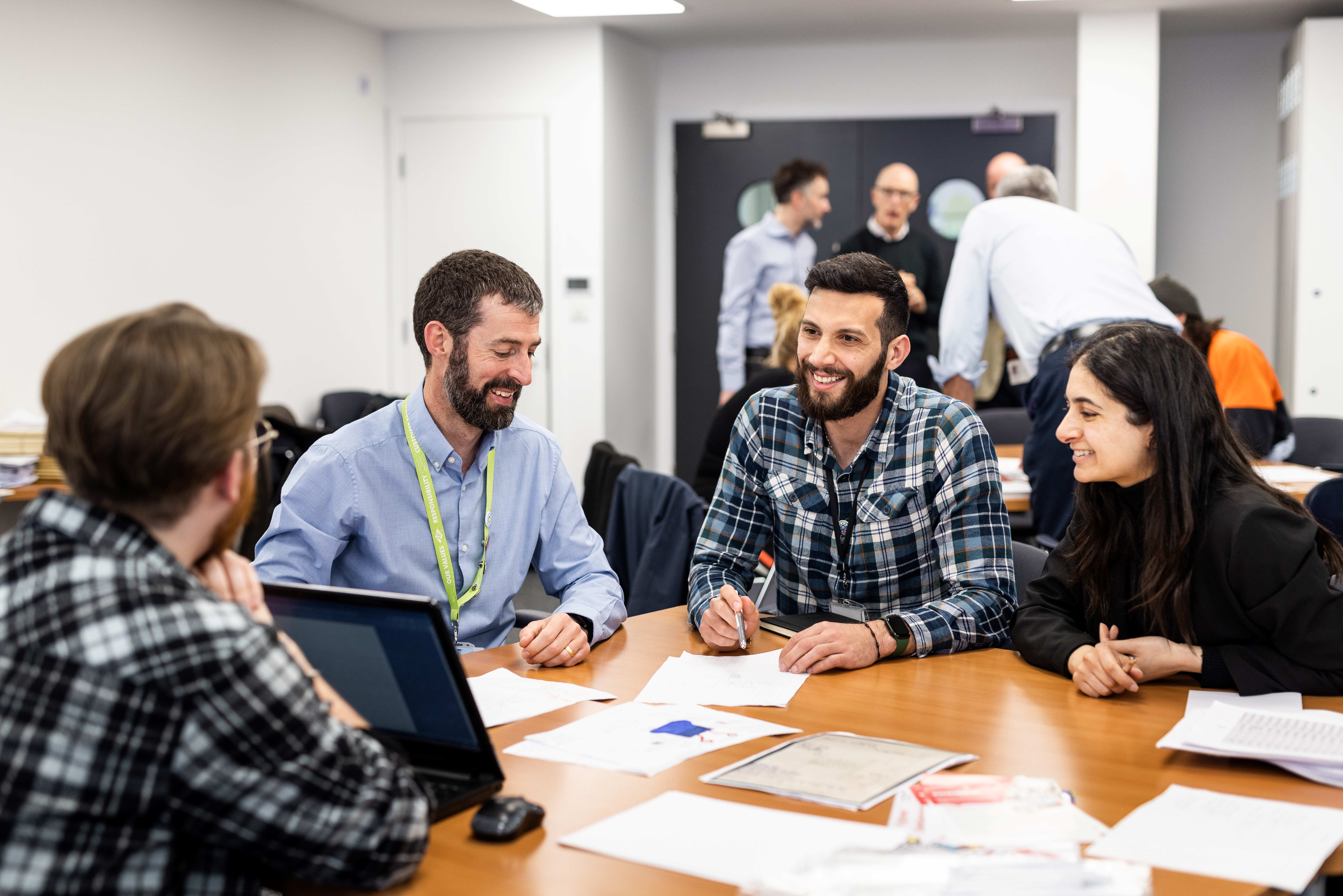 A group of people sat around an office table, smiling whislt looking at competition entries
