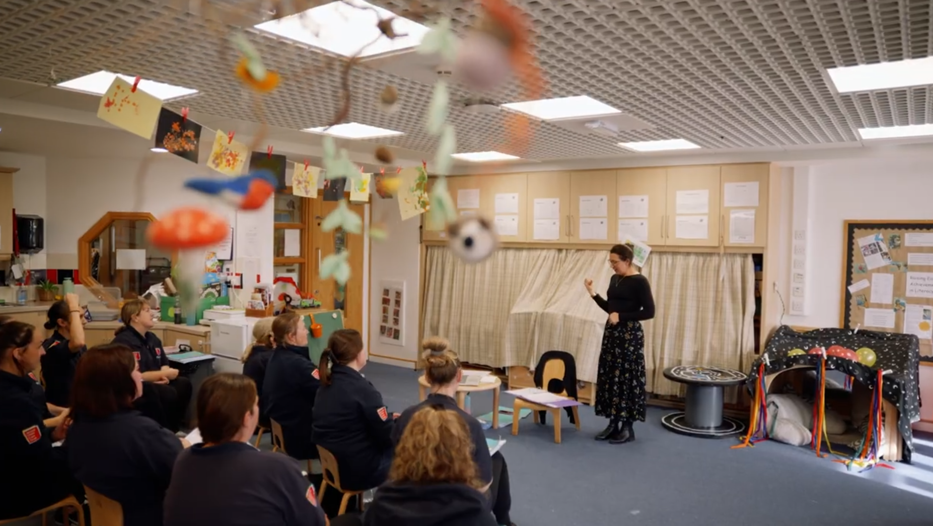 A lady is teaching in front of a group of support workers teaching them Makaton Signing.