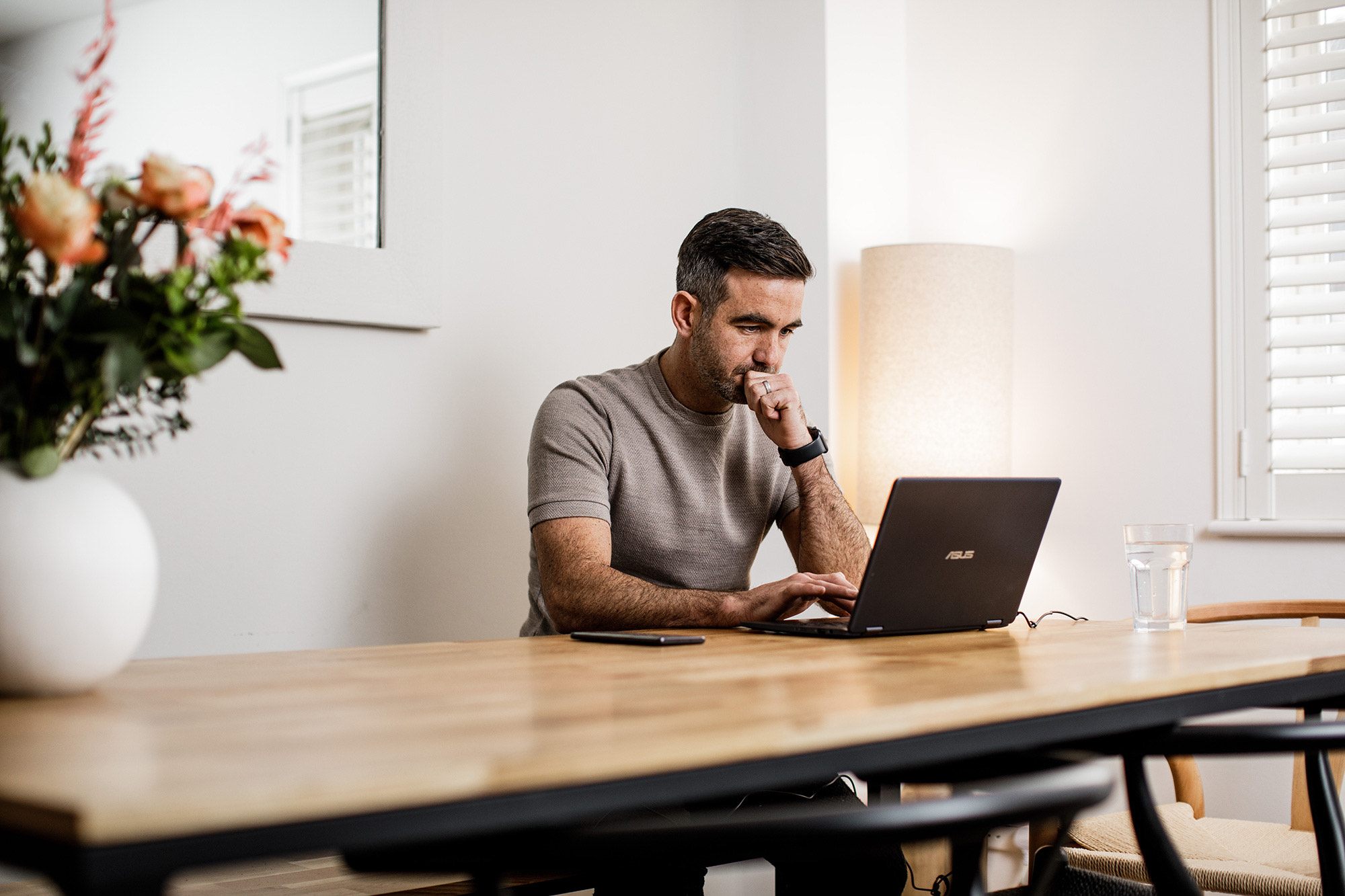 Man searches on a laptop whilst sat at the kitchen table.