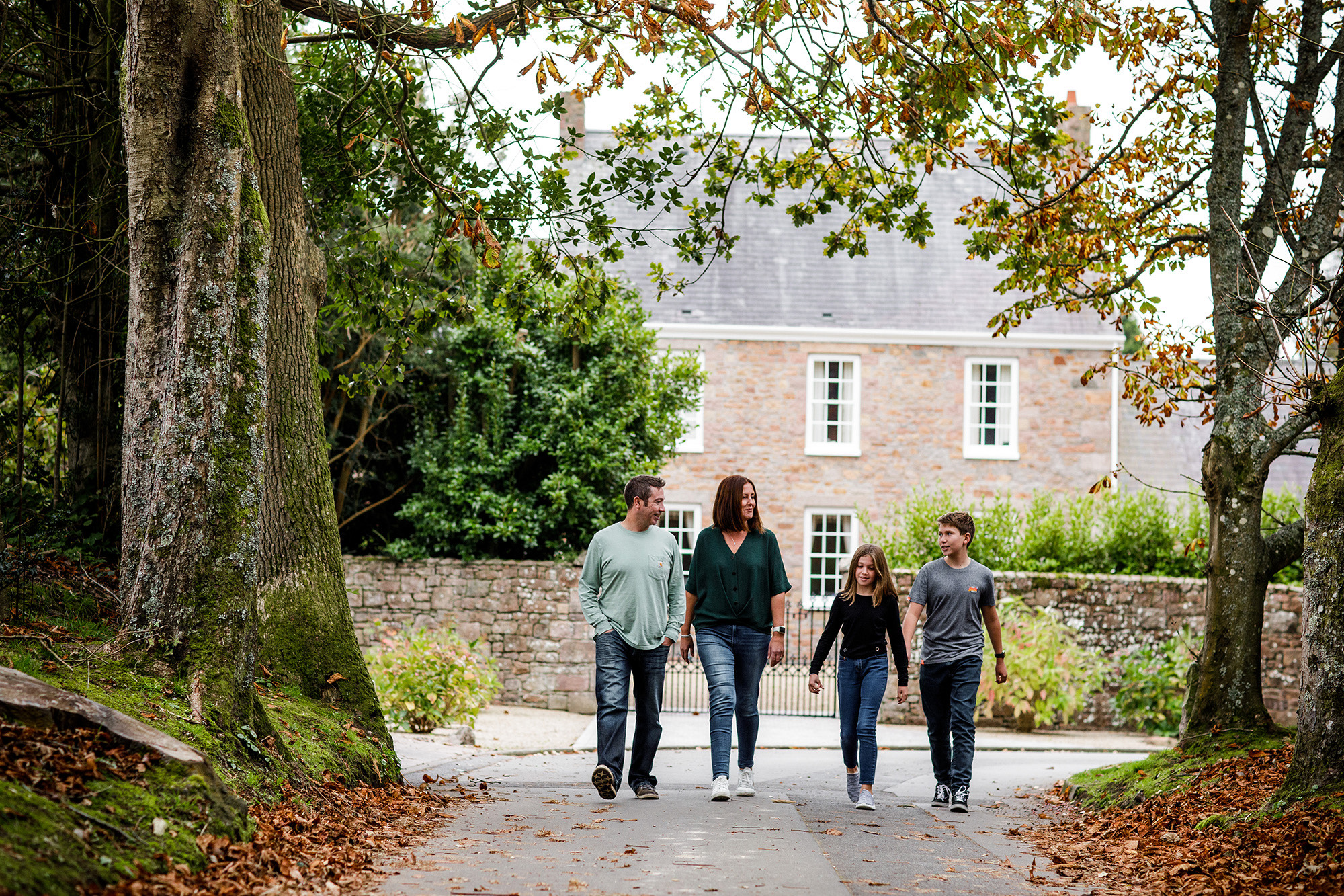 A family walk past a period house in the Jersey countryside.