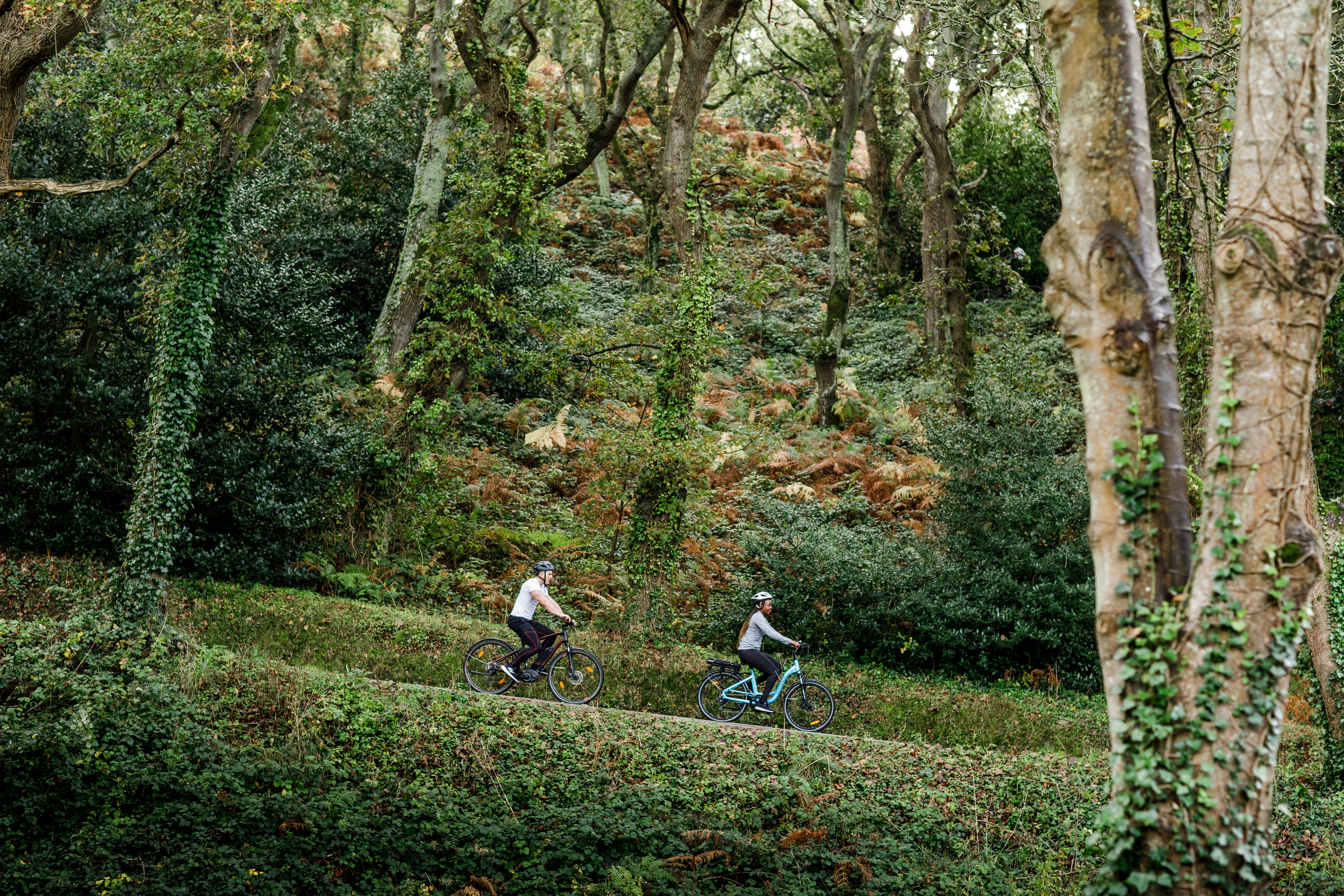 Couple on electric bikes ride down hill