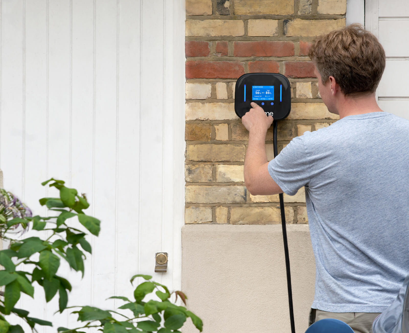 Man presses the screen on an Ohme electric vehicle charger