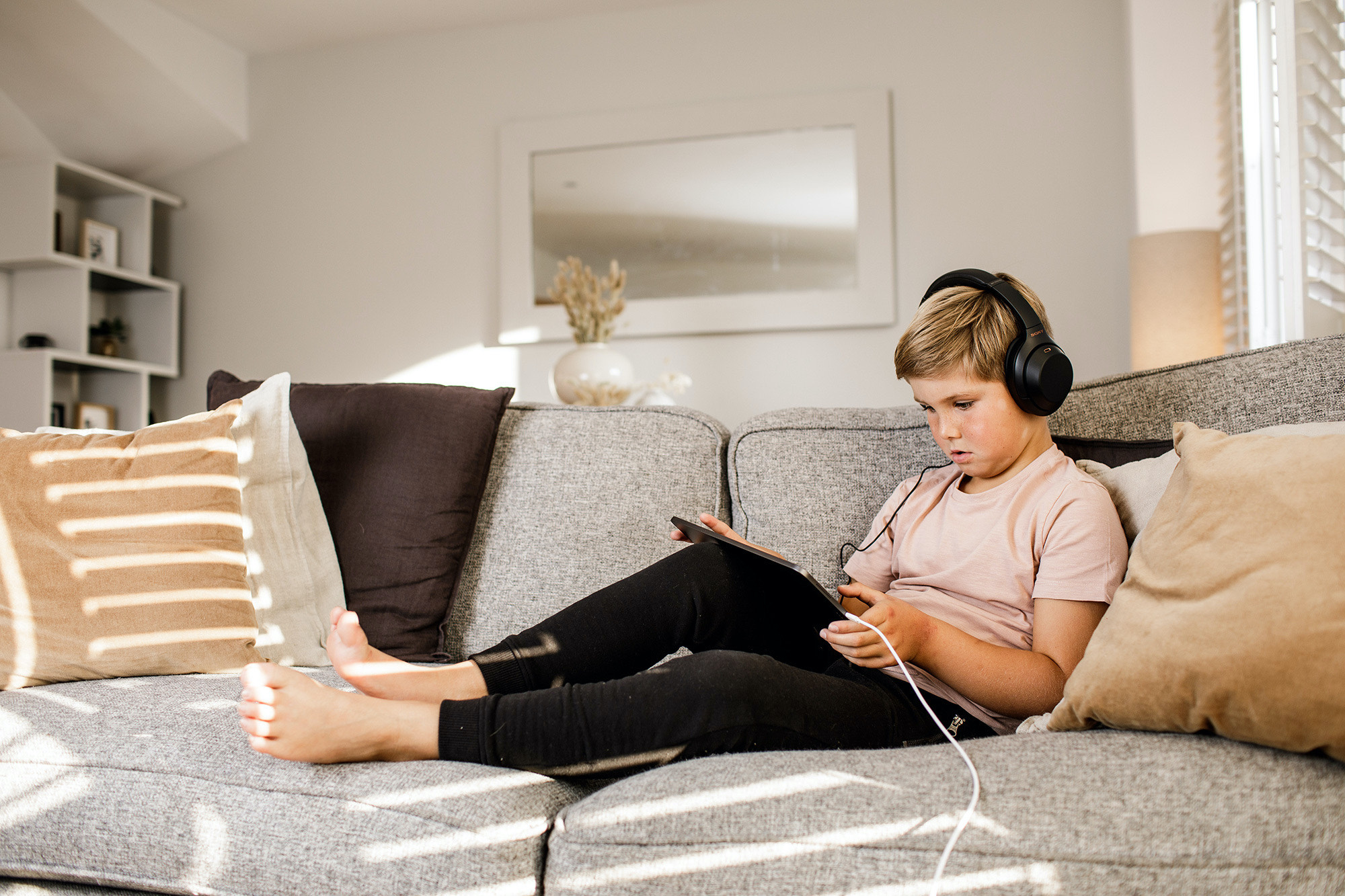 Boy uses iPad on couch