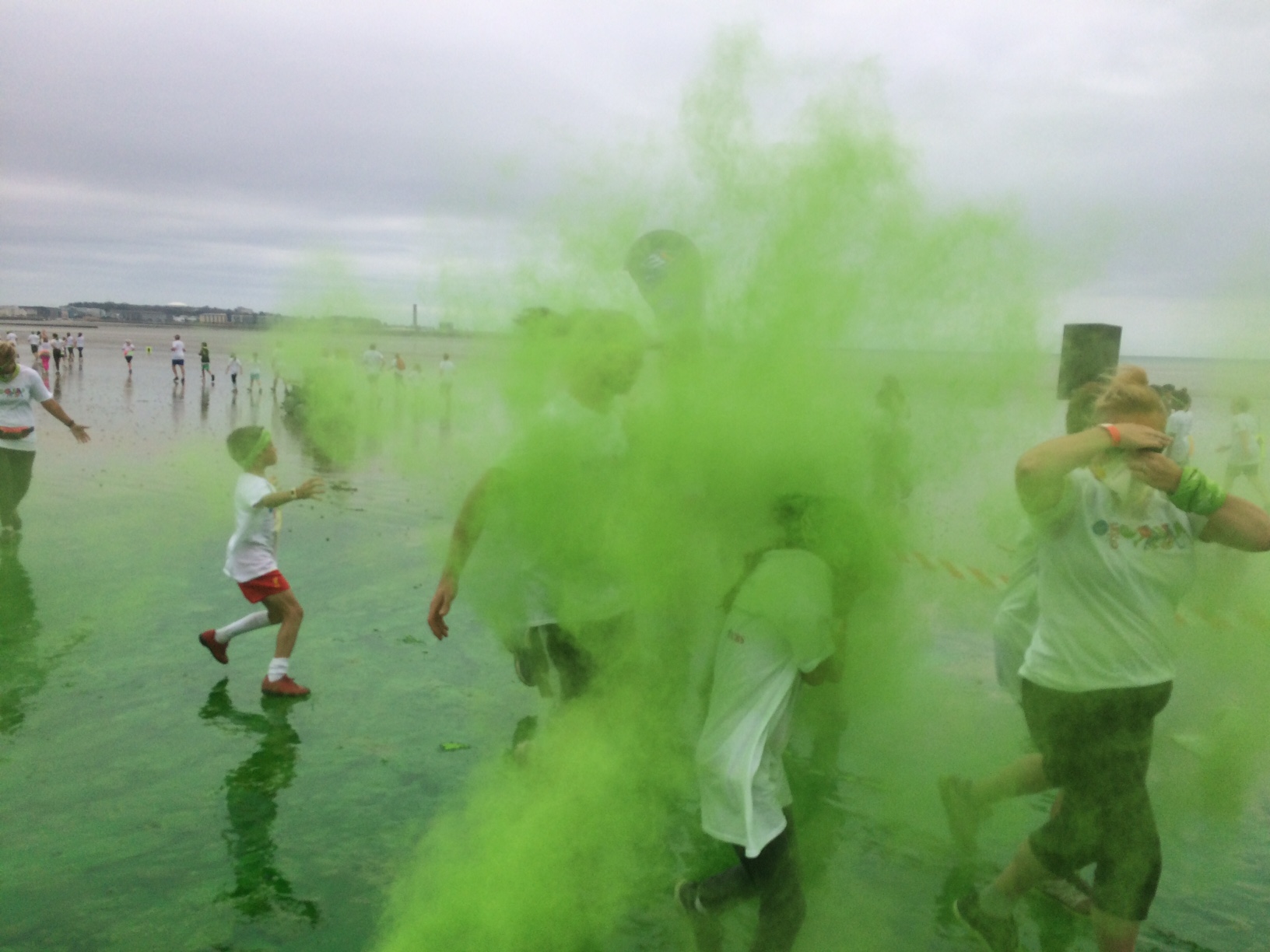 Children throw green paint at each other during the colour run