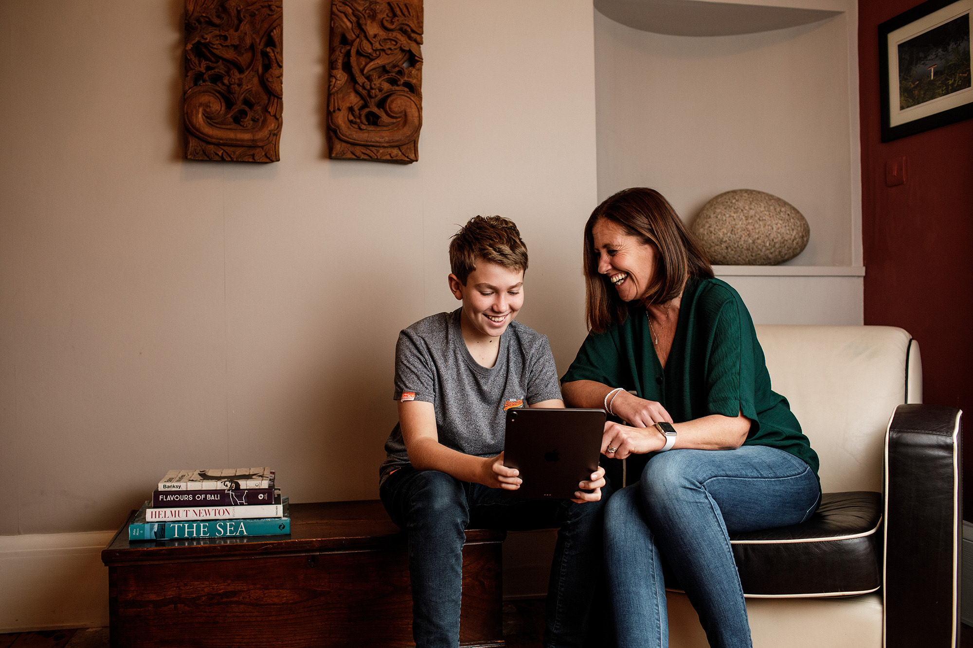 A mother and son laugh together over something they've seen on a tablet.