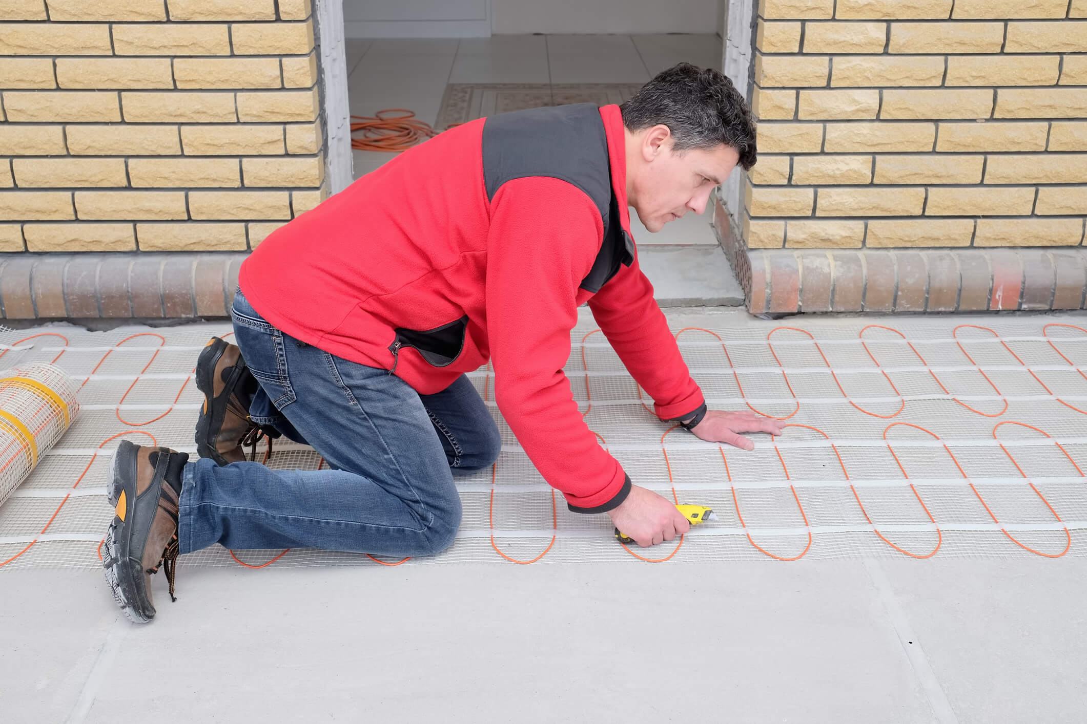 An electrician installs electric underfloor heating.