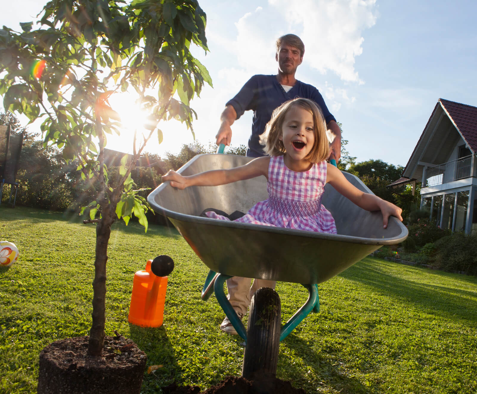 Father pushing daughter in a wheelbarrow