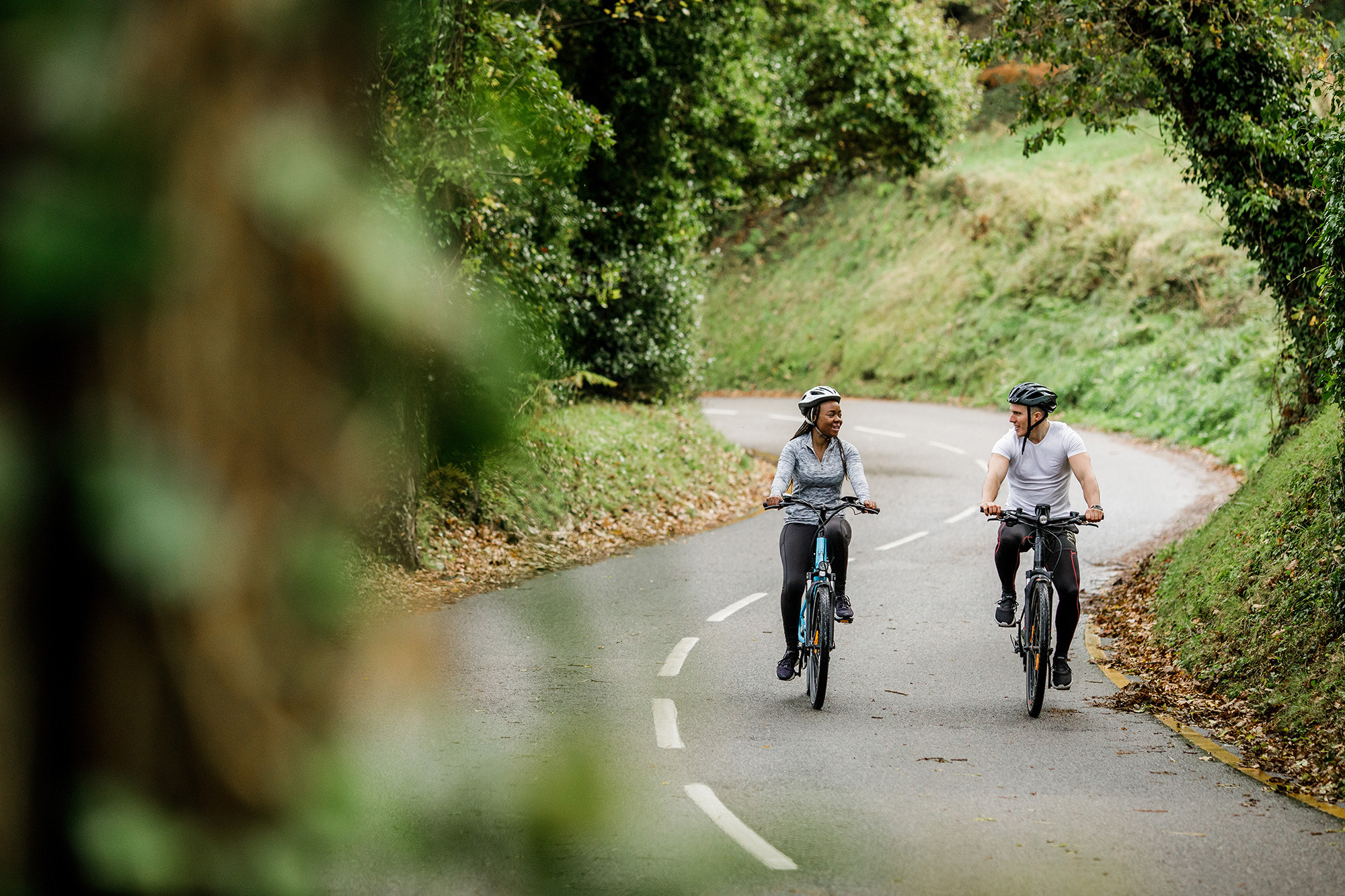 A man and a women cycle electric bicycles through Jersey's country lanes