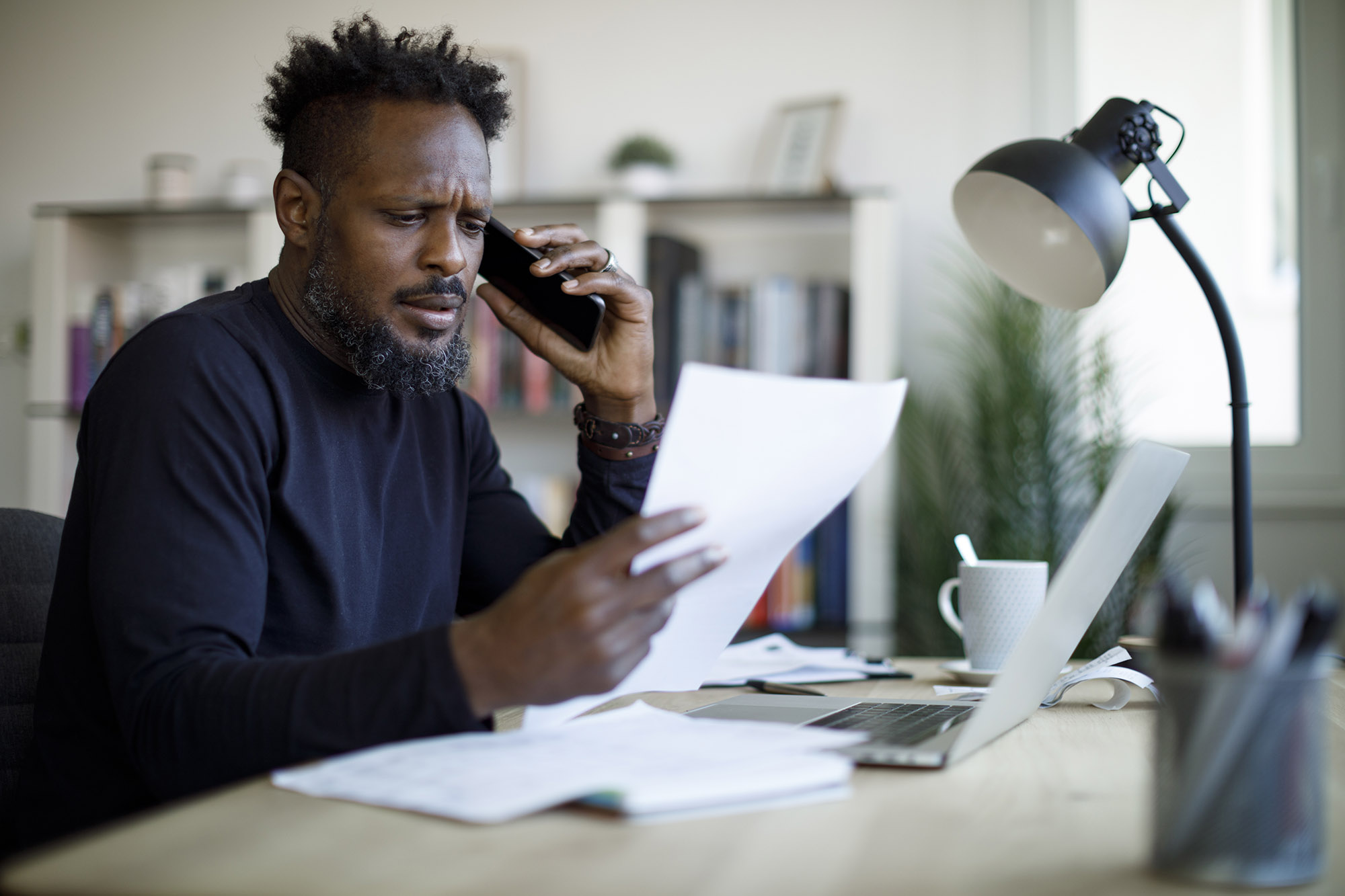 Man looks at a bill whilst on the phone