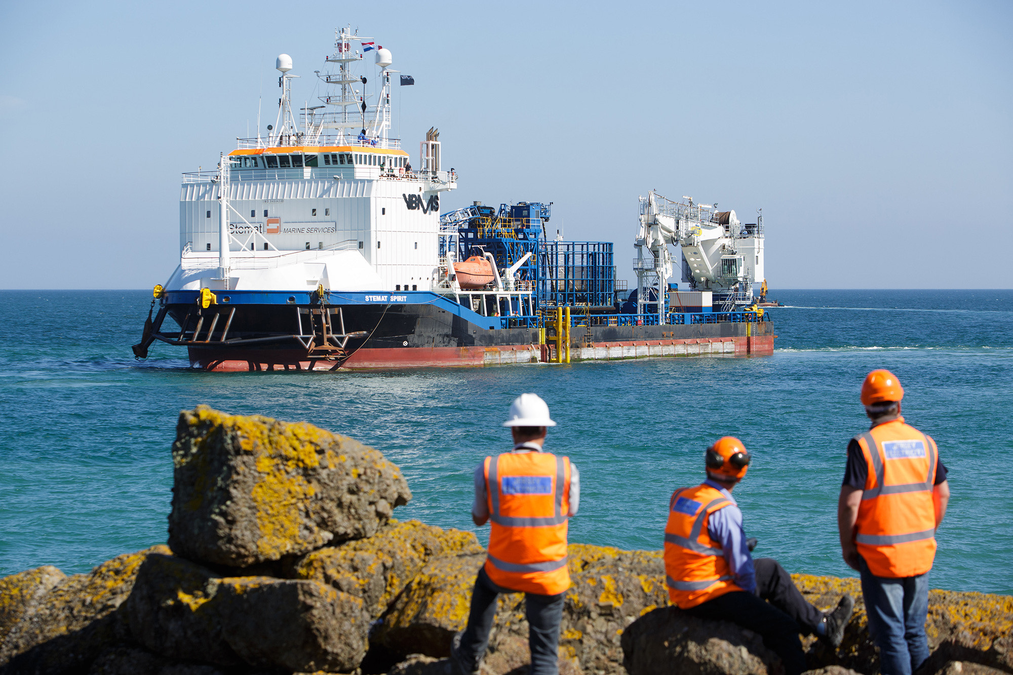 Three members of the Normandie 1 project team watch as Stemat arrives in Jersey.