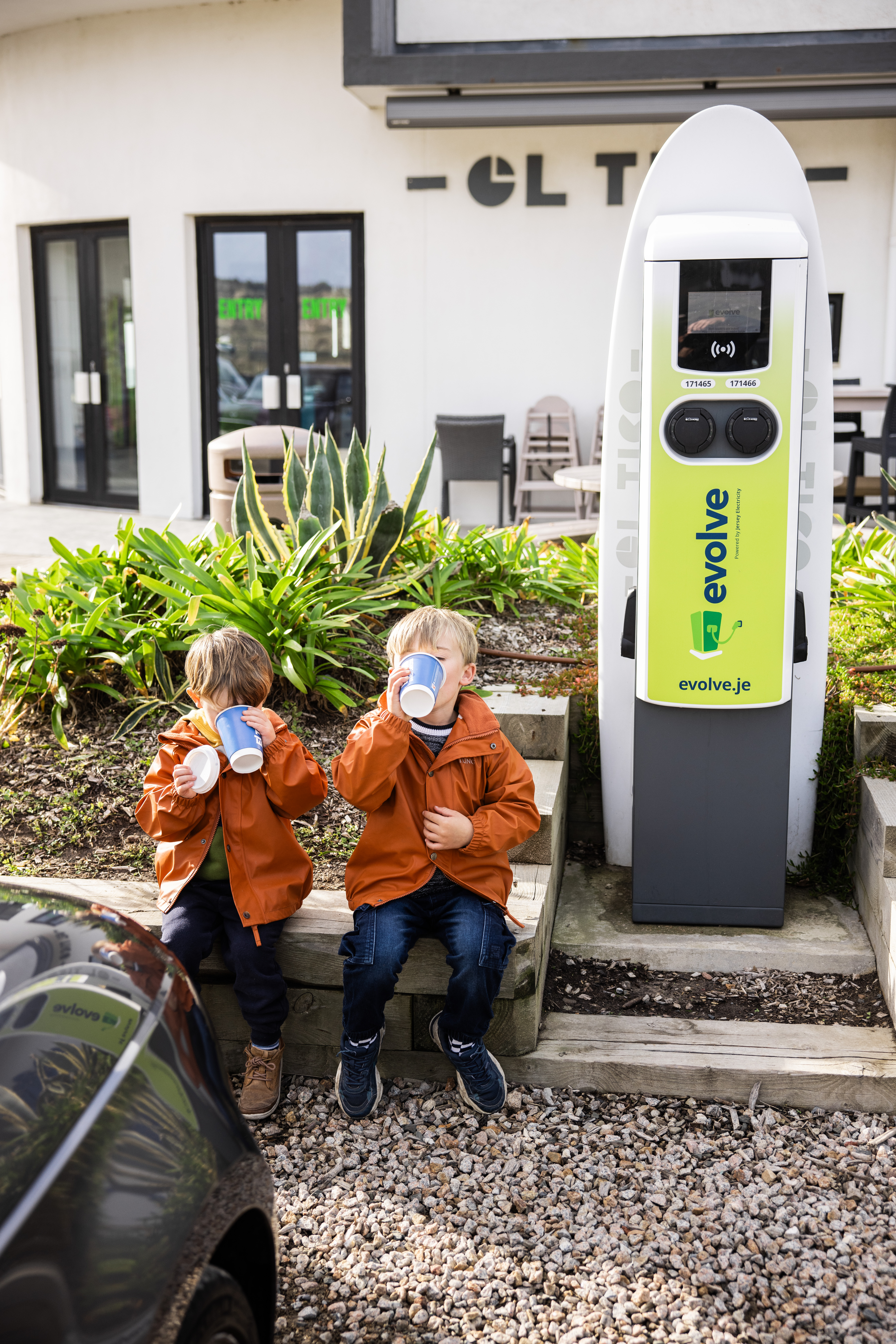 Evolve El Tico charge point with two little boys sitting by enjoying a hot drink