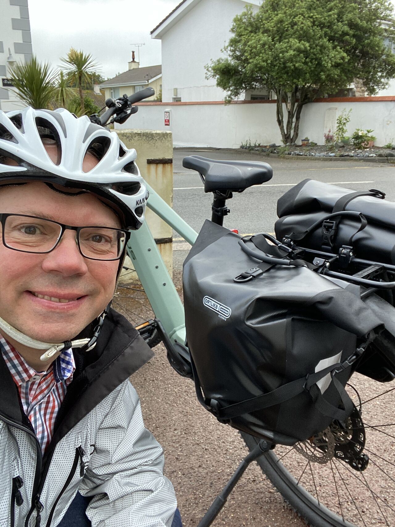 Chris Ambler, Jersey Electricity CEO, wearing a bicycle helmet and kneeling next to his electric bike