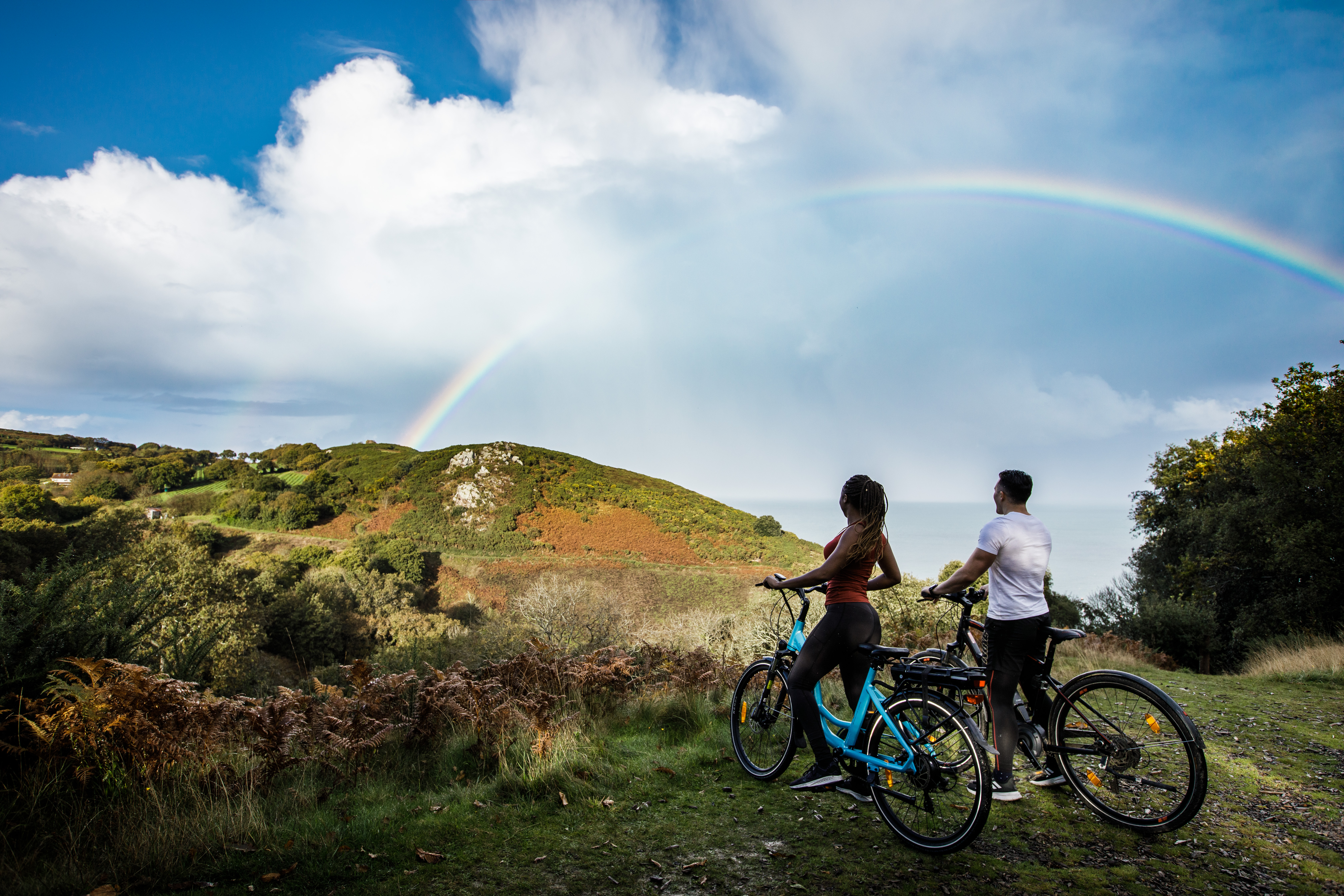 Couple On Bikes With Rainbow