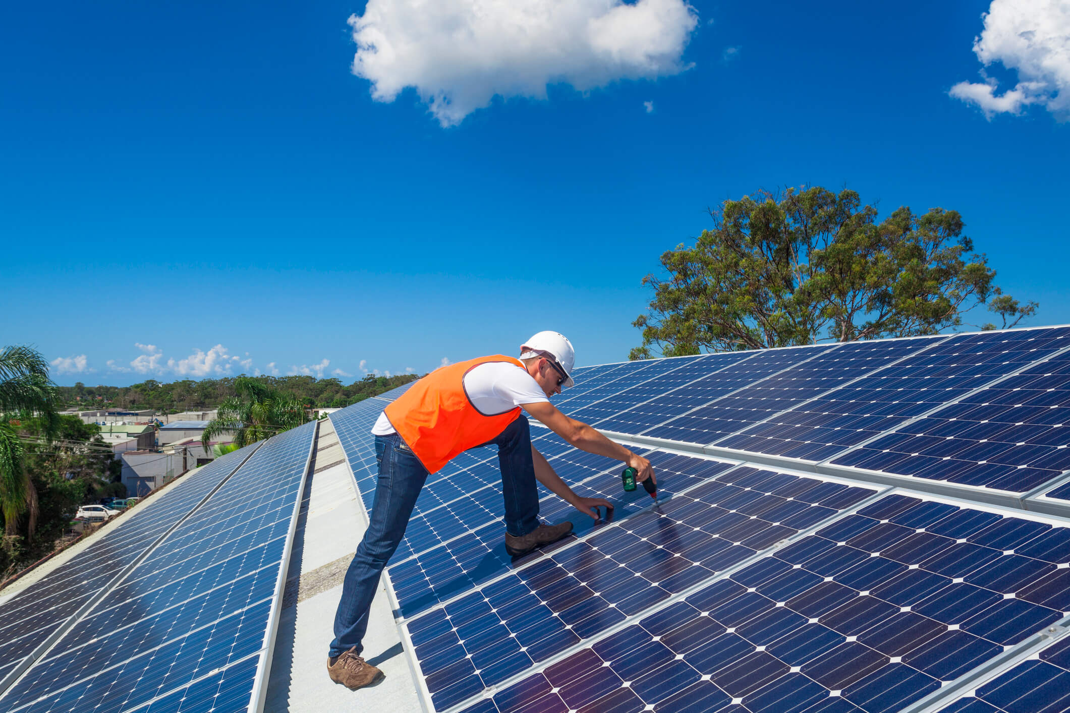 A tradesperson installs solar panels on a large roof.