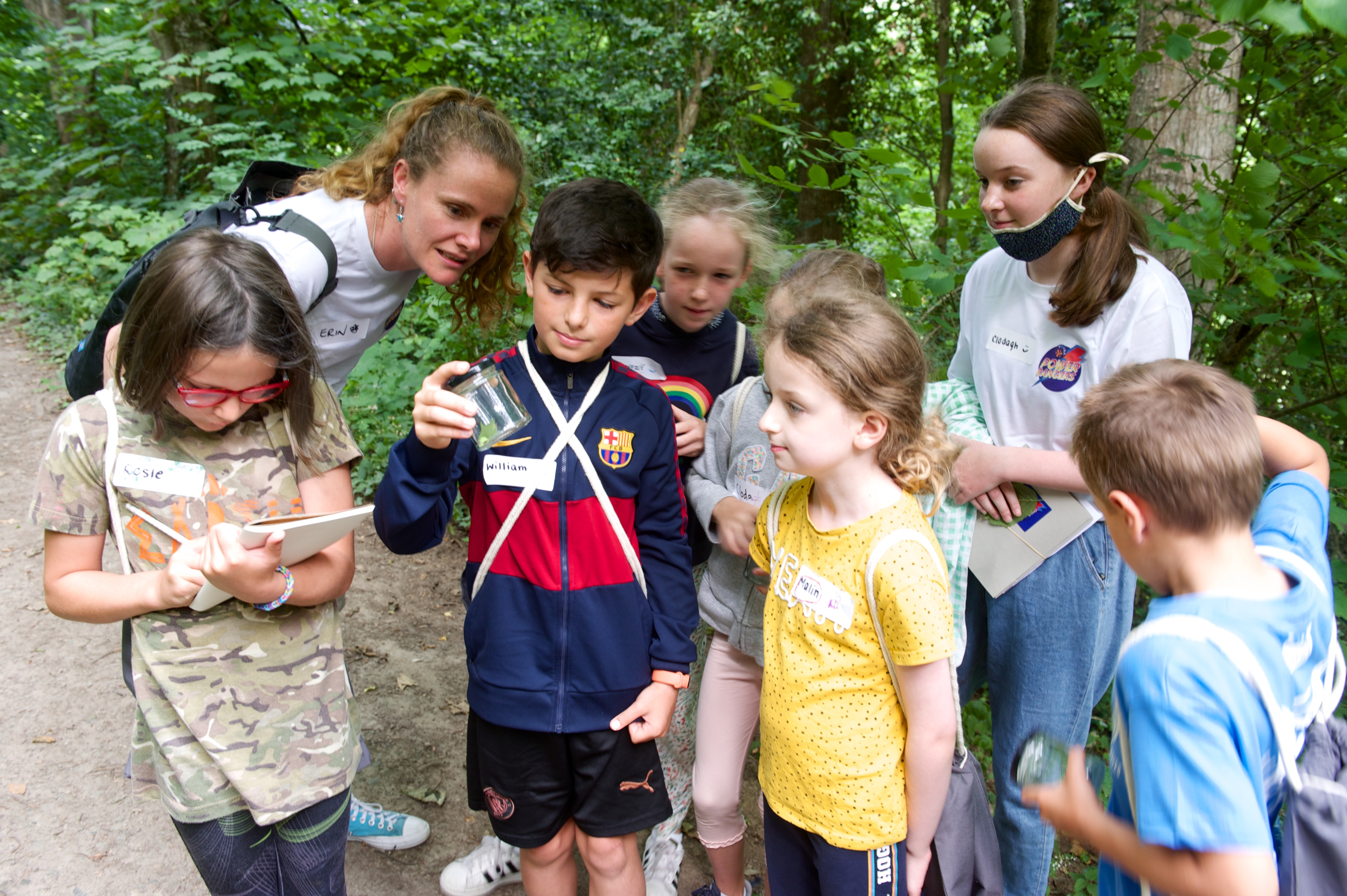 Erin and seven children inspect a jar of bugs