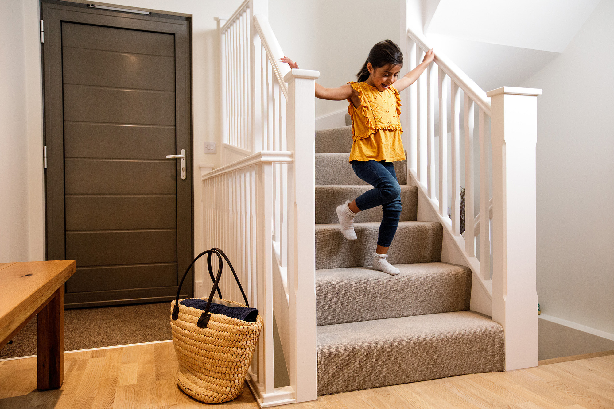 A young girl runs down the stairs in a modern electric home.