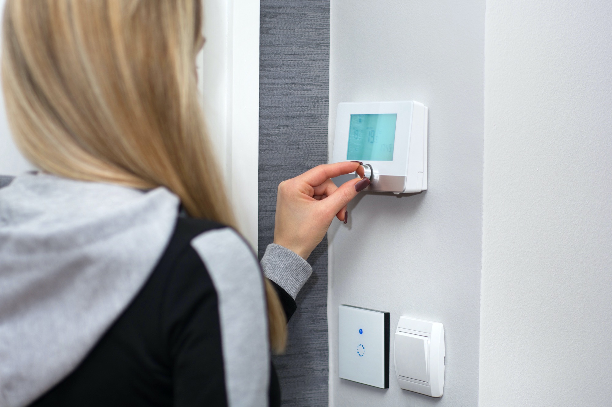 Woman using heating thermostat