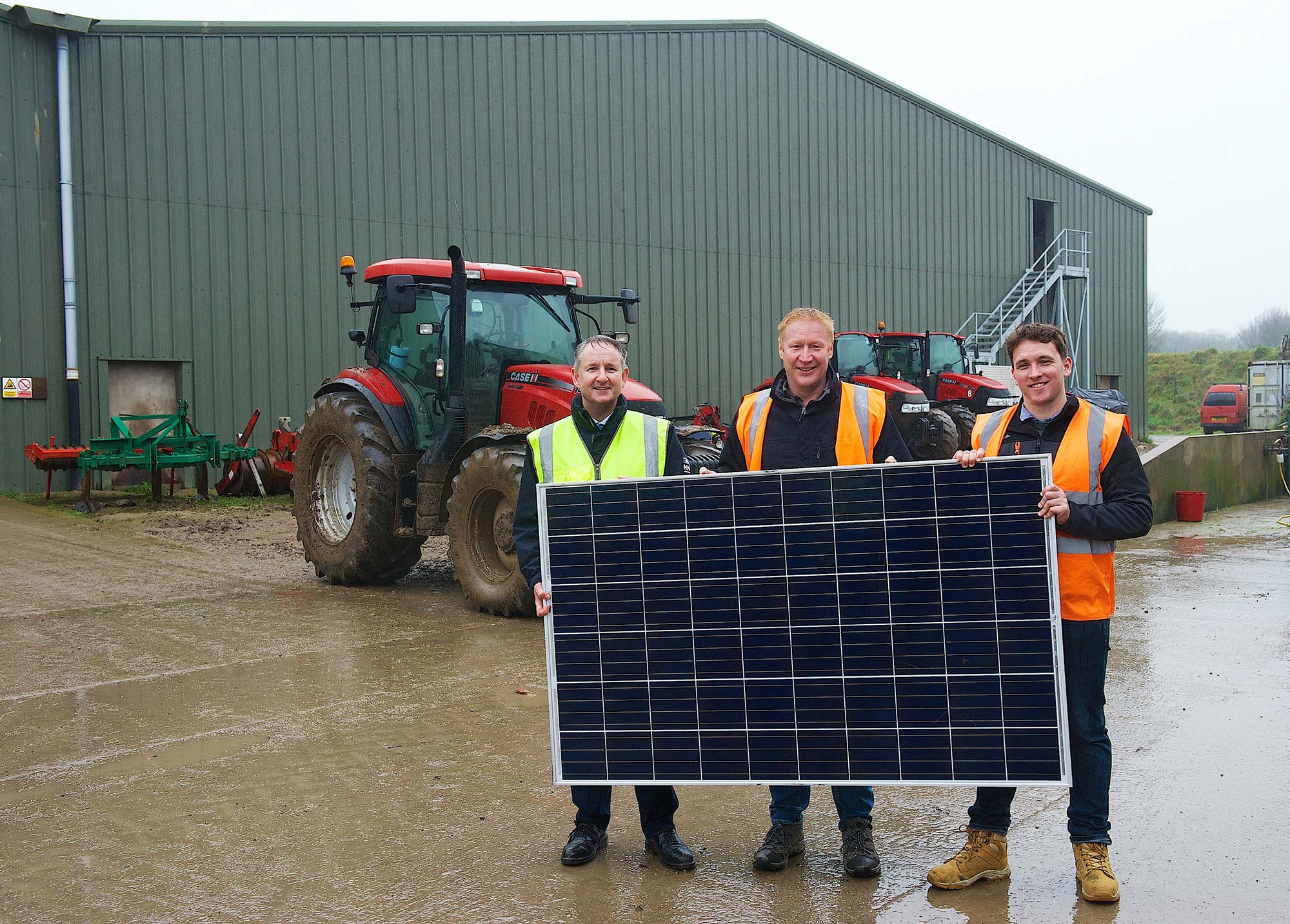Three workers from JE, Sunworks and Woodside Barn hold a Solar PV panel.