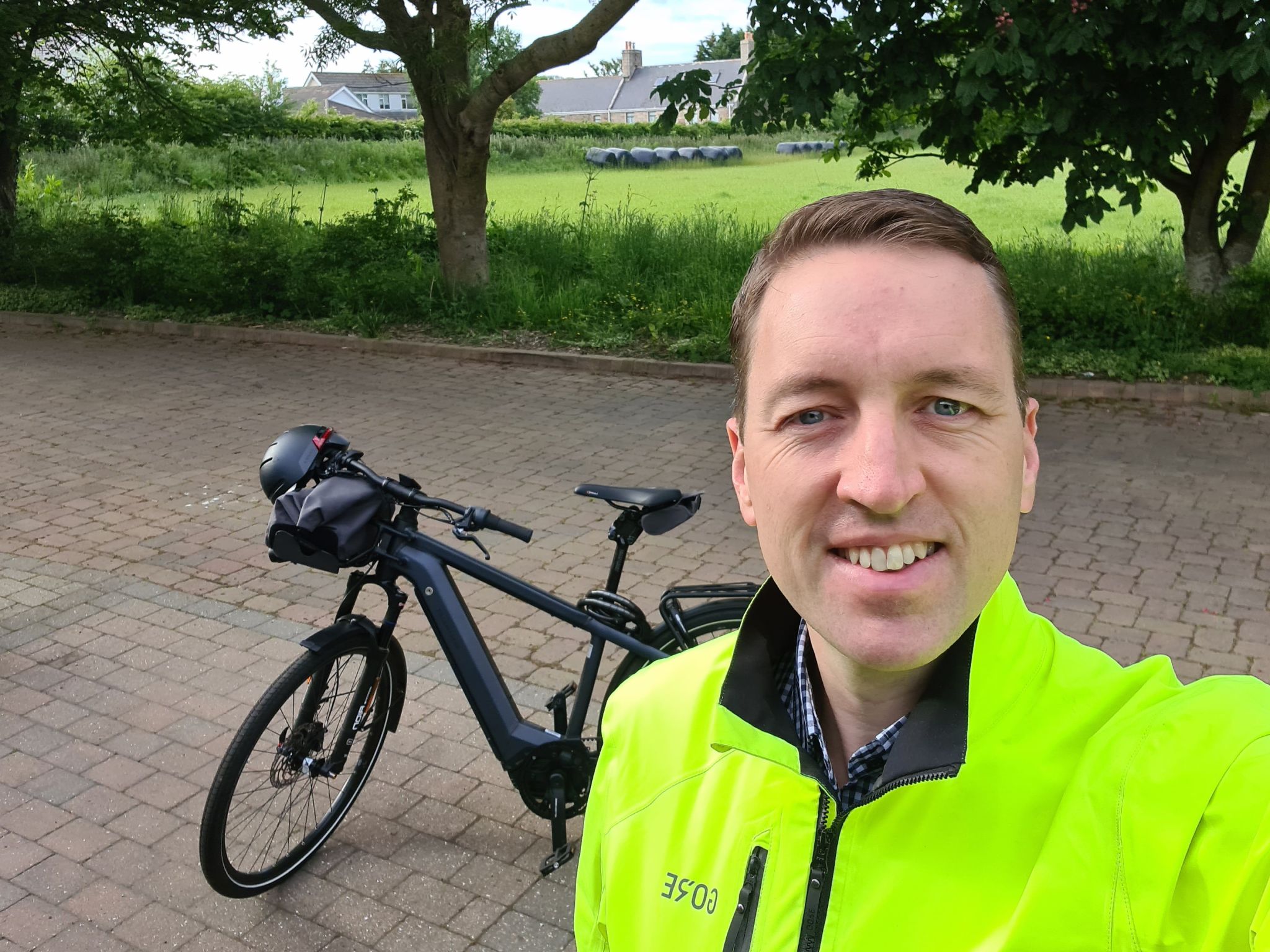 Stuart Murphy, Jrsey Electricity Head of Customer Experience and Communications. wearing a reflective jacket standing next to his electric bike