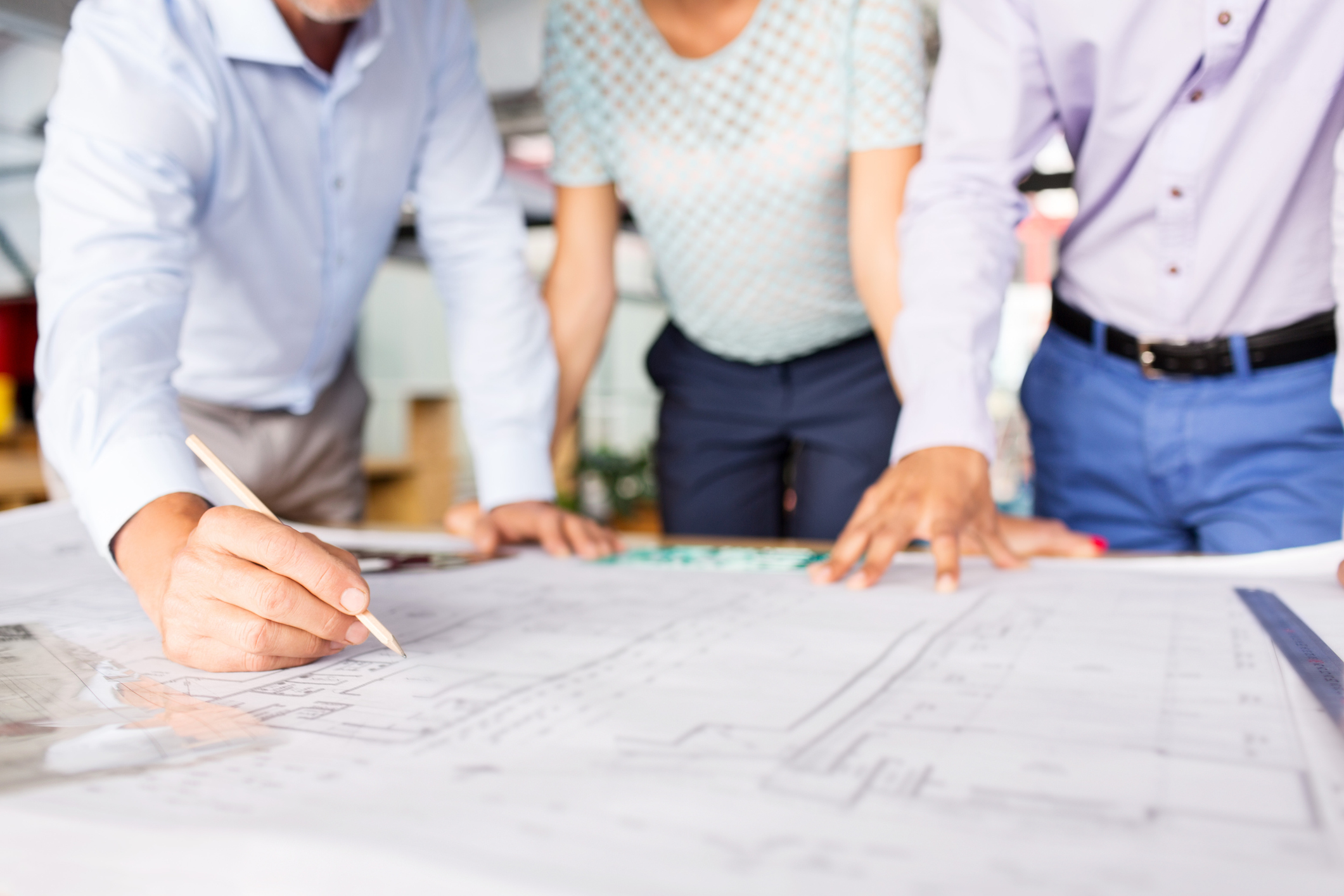 Three engineers look at a set of buidling drawings.